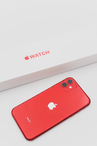 closed Apple watch product red box and iphone on a white tabletop with text space