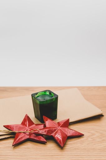 green candle and red painted decorative wooden star on a wooden background with copy space