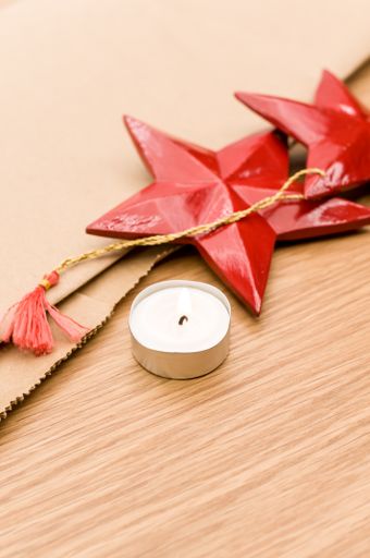 red painted decorative wooden star and tea light on a wooden background with copy space
