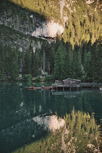 A vertical shot of the beautiful mountains and lake with a cabin and boats in South Tyrol, Italy