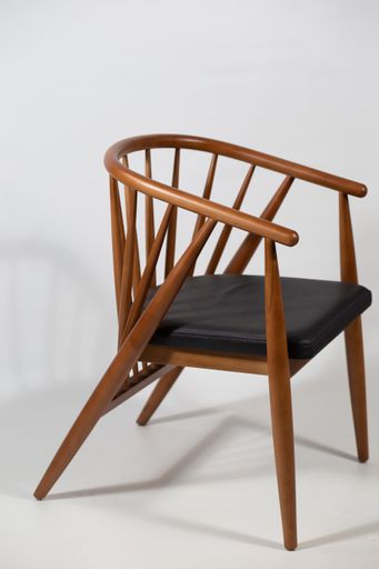 A vertical shot of a wooden chair behind a white background