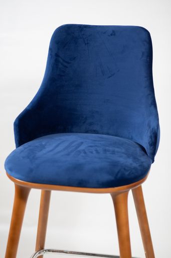 A vertical shot of a blue chair with wooden legs behind a white background