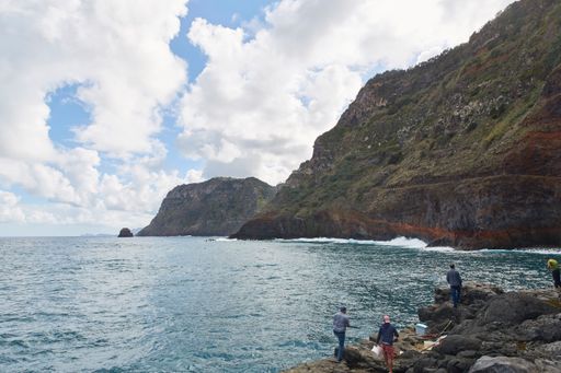 A beautiful view of rocky cliffs in the blue water against a cloudy sky on a sunny day