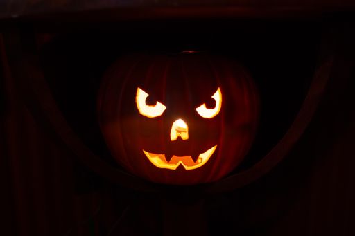 A close-up shot of a scary carved lit Halloween pumpkin in the darkness