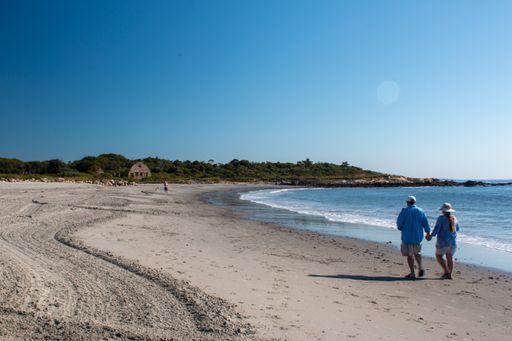 A back view of a cute couple walking along the sandy beach in the morning