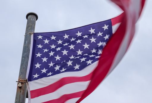 A low angle shot of a wavy flag under the cloudy sky