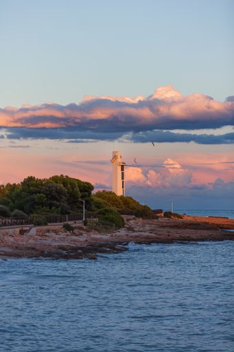 A vertical shot of a lighthouse by the sea at sunset in Alcossebre, Spain