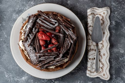 A top view of chocolate marquise cake with red berries resting on a rustic table
