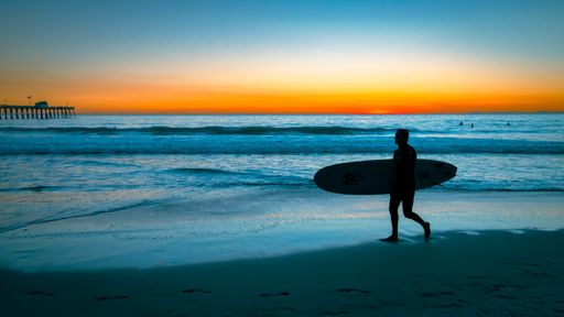 a silhouette of a guy going to surf at the San Clemente beach