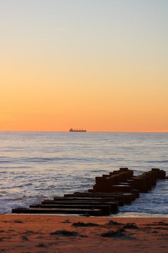 A vertical shot of a jetty at Rehoboth Beach with a mesmerizing view of the sunrise in Rehoboth, US