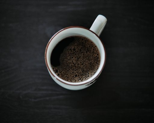 A closeup of the cup of coffee on the black table. Top view.