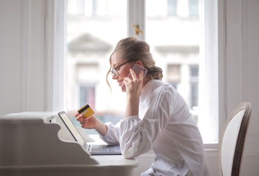 A businesswoman talking on the phone holding a credit card and smiling
