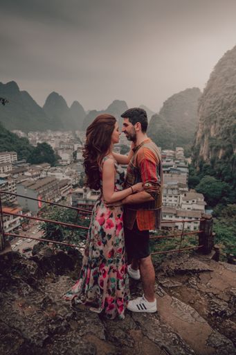 A portrait of a young couple embracing on the stairs surrounded by hills and buildings outdoors