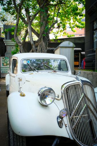 A vertical closeup of a white vintage car parked on the street. The photo was taken with the Fujifilm X-T30 mark 2.