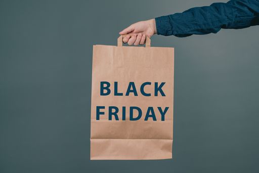 Young man is holding a shopping bag with the phrase black friday, dark colored background, big sale