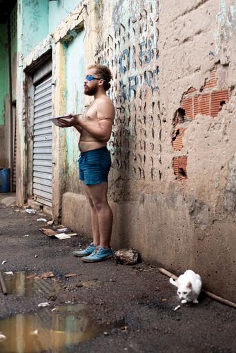 A shirtless man holding white basin of water, wearing diving goggles protesting at Sao Joaquim fair