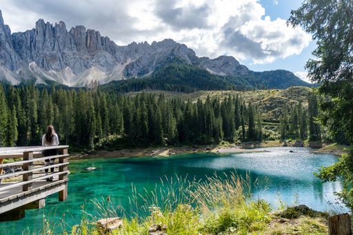 A majestic view of Lake Karersee (Lago di Carezza) in the Dolomites, Italy, with a girl admiring the scenery