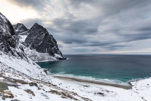 A landscape of the Kvalvika beach under a cloudy sky on a rainy day in winter in Lofoten, Norway