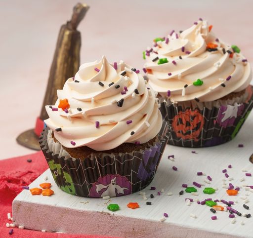 A closeup shot of tasty cupcakes decorated with colorful sprinkles against a pink background