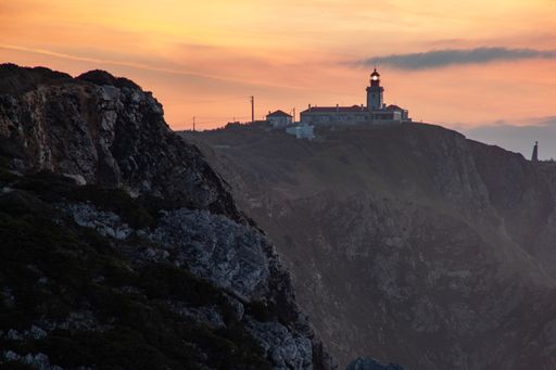 A beautiful shot of cliffs and a lighthouse during the sunset in Cabo da Roca Sintra