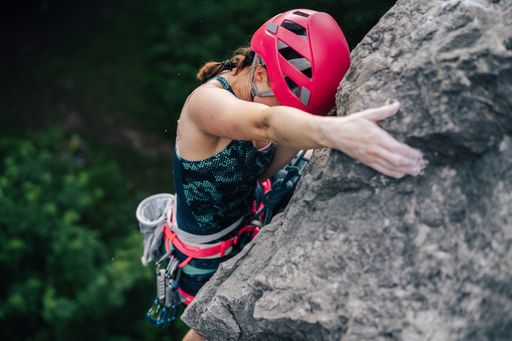 Woman climber rock climbing steep wall. Adventure sport activity, adrenaline. Girl climbing with a rope, helmet and other rock climbing equipment.