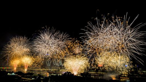 A beautiful shot of exploding yellow fireworks at night over the Brisbane river