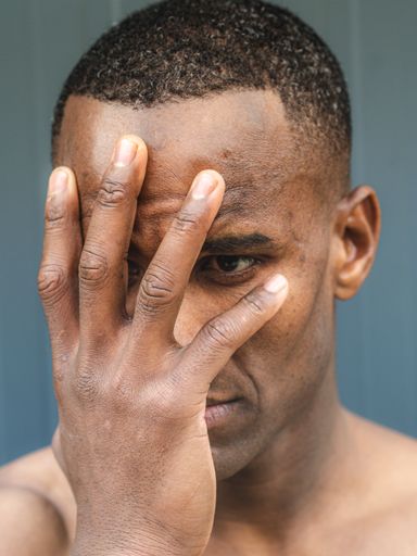 A portrait of an African man covering the face with his hand