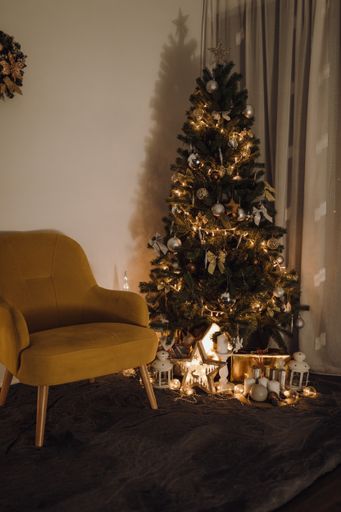 A yellow armchair near the Christmas tree and holiday decor in Scandinavian style