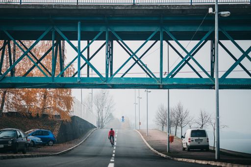 A front view of a young cool male cyclist in red sportswear riding a bicycle on a gloomy day