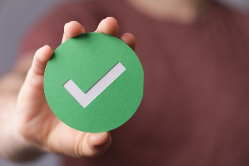 A sign of the checkmark made of paper in the hands of a man