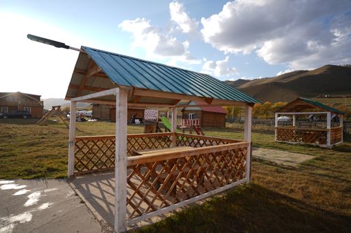 A wooden pavilion with benches and a table in a park