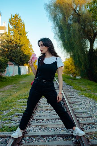 A vertical shot of a young beautiful female posing on train tracks