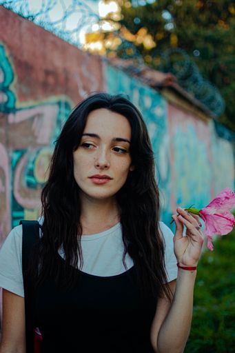 A vertical shot of a young beautiful female posing with a pink Hibiscus flower