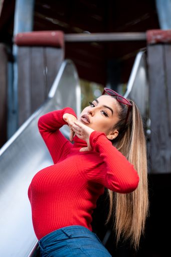 A vertical shot of a lovely lady wearing a turtleneck, jeans, and sunglasses posing in a playground