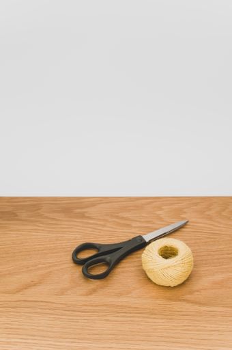 scissors and rough cotton decorative yarn on a wooden background with text space