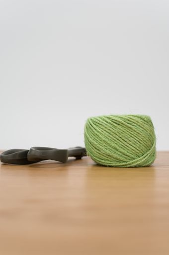 scissors and rough cotton decorative yarn on a wooden background with text space