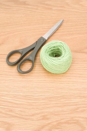 scissors and rough cotton decorative yarn on a wooden background with text space