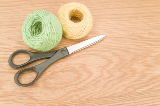 scissors and rough cotton decorative yarn on a wooden background with text space