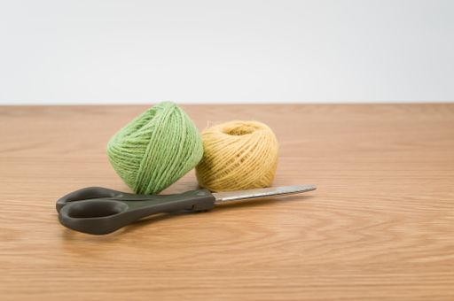 scissors and rough cotton decorative yarn on a wooden background with text space
