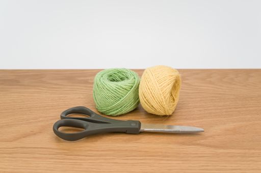 scissors and rough cotton decorative yarn on a wooden background with text space