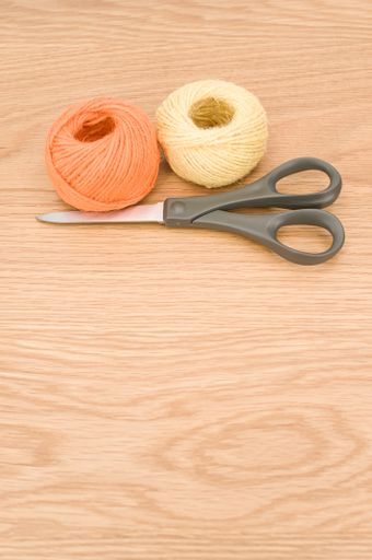 scissors and rough cotton decorative yarn on a wooden background with text space