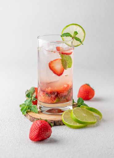 A vertical shot of a mojito with strawberries on the white background