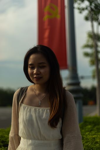A vertical shallow focus shot of an Asian female wearing a white dress on the streets