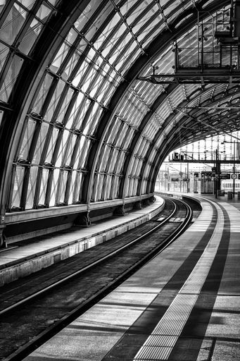A vertical grayscale shot of a train station in Berlin, Germany