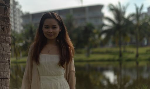 A shallow focus shot of an Asian female wearing a white dress on the streets