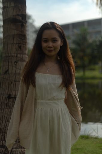 A vertical shallow focus shot of an Asian female wearing a white dress on the streets