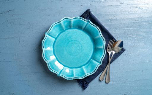 A top view of a plate with a fork and a spoon on a blue wooden table