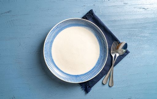 A top view of a plate with a fork and a spoon on a blue wooden table