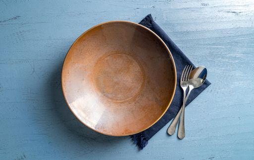 A top view of a plate with a fork and a spoon on a blue wooden table