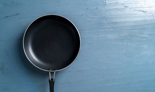 A top view of a black frying pan on a blue wooden table